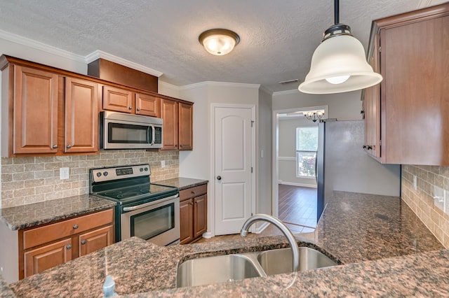 2731 Ashton Dr, Hephzibah, GA 30815 - kitchen with appliances with stainless steel finishes, a sink, a textured ceiling, brown cabinetry, and dark stone countertops