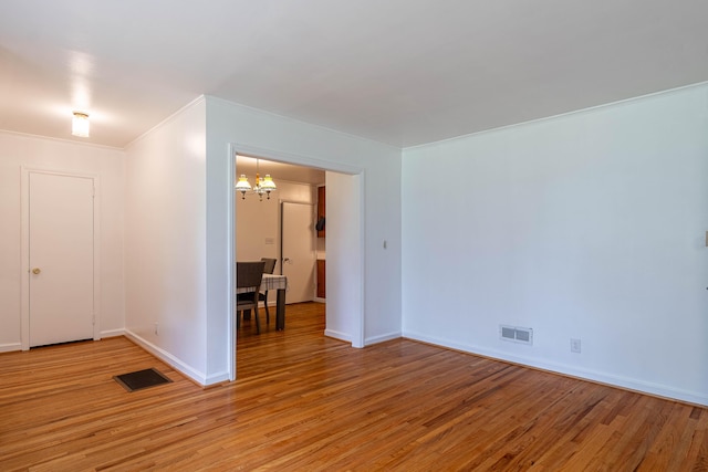 spare room with light wood-type flooring and a notable chandelier