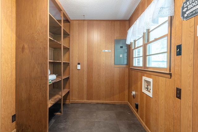 interior space with electric panel, wood walls, hookup for a washing machine, and a textured ceiling