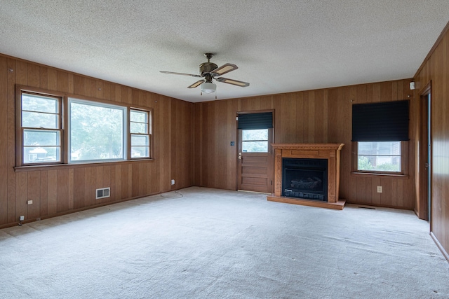 unfurnished living room featuring a textured ceiling, ceiling fan, a healthy amount of sunlight, and light carpet