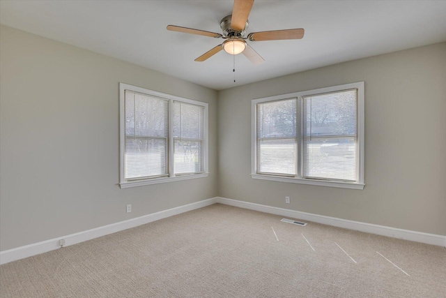 unfurnished room with baseboards, light carpet, visible vents, and a ceiling fan