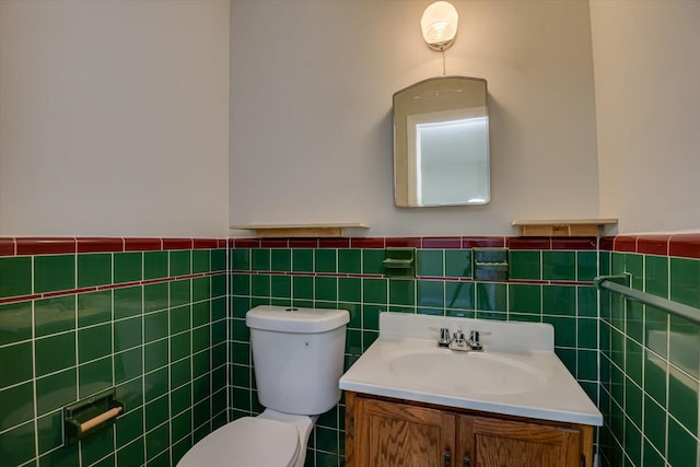 half bathroom with a wainscoted wall, toilet, tile walls, and vanity