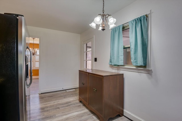 dining space featuring baseboards, a notable chandelier, and light wood-style flooring