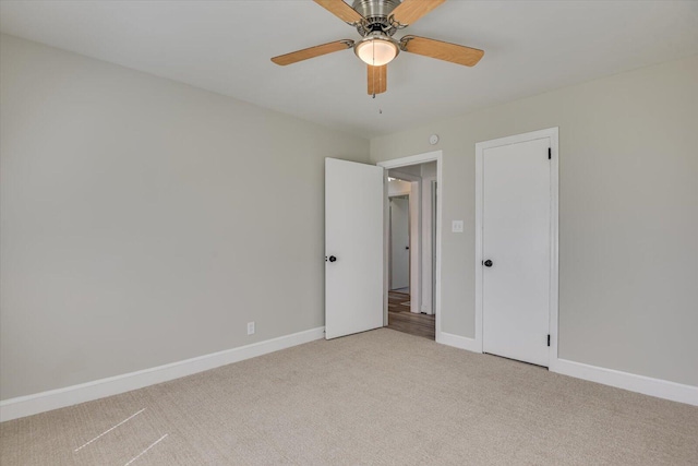 unfurnished bedroom featuring light colored carpet, a ceiling fan, and baseboards