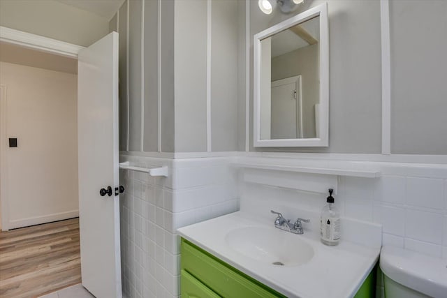 bathroom with tile walls, toilet, vanity, and wood finished floors