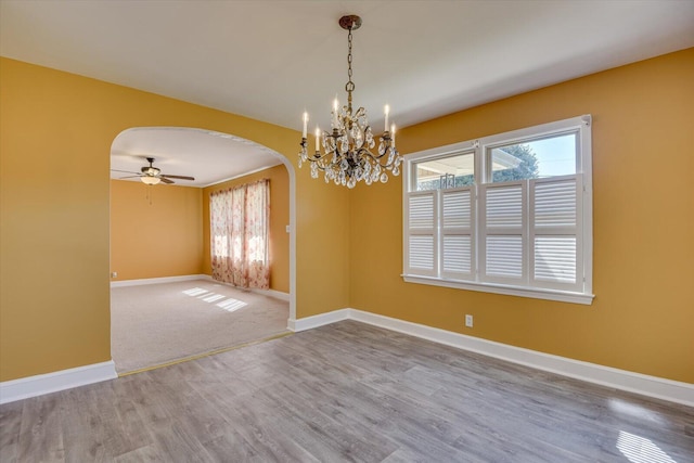 empty room with baseboards, arched walkways, plenty of natural light, and wood finished floors