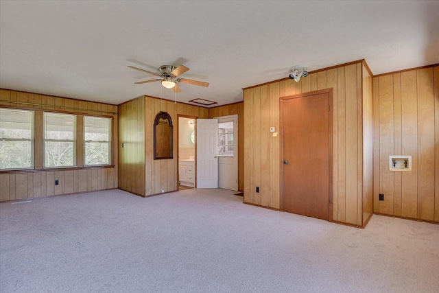 carpeted empty room with baseboards, wooden walls, and ornamental molding