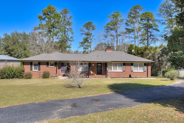 single story home with a front lawn, fence, brick siding, and a chimney