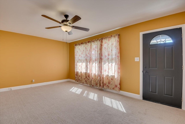 carpeted foyer entrance featuring baseboards, a healthy amount of sunlight, and ceiling fan