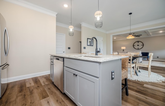 6047 Bakerville Ln, North Augusta, SC 29860 - kitchen with appliances with stainless steel finishes, a center island with sink, crown molding, dark wood finished floors, and light stone counters