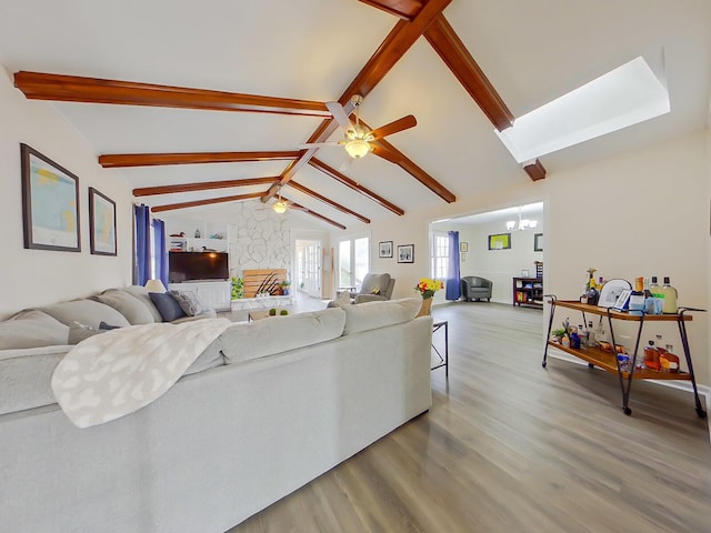 living area featuring vaulted ceiling with beams, ceiling fan with notable chandelier, and wood finished floors