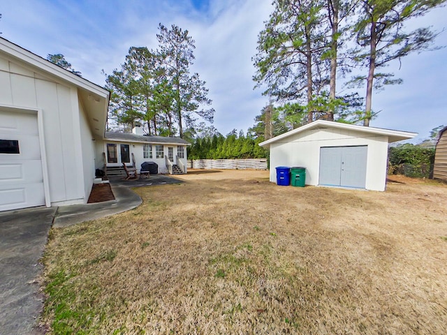view of yard with an outbuilding, a storage shed, entry steps, fence, and a garage