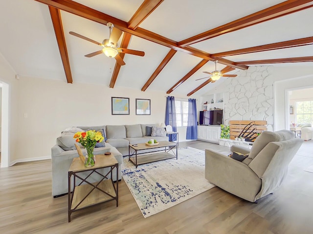 living room featuring vaulted ceiling with beams, ceiling fan, a fireplace, and wood finished floors