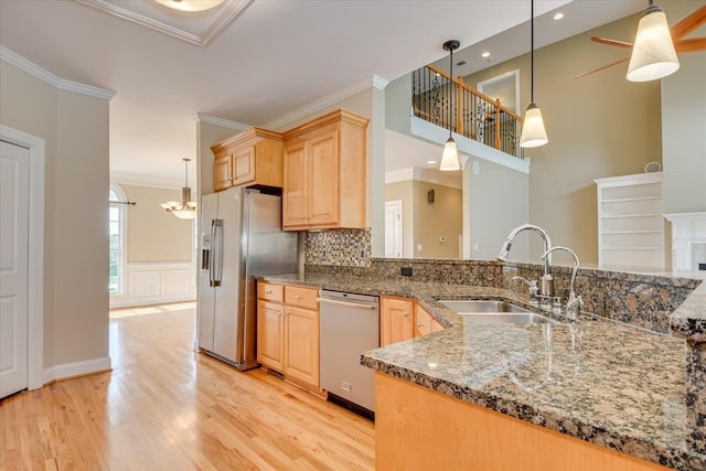 kitchen featuring stainless steel appliances, a sink, light brown cabinetry, crown molding, and light wood-style floors