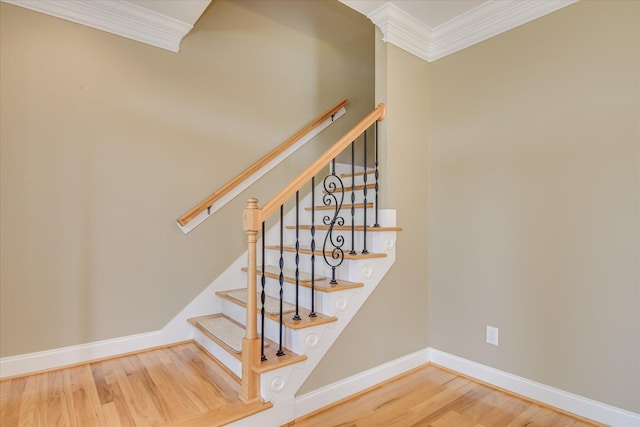 staircase with crown molding, wood finished floors, and baseboards