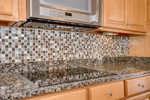 kitchen featuring stainless steel microwave, backsplash, black electric cooktop, and light brown cabinetry