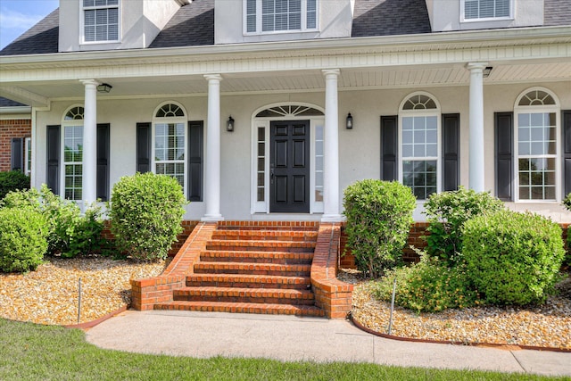 doorway to property featuring a shingled roof, stucco siding, and a porch