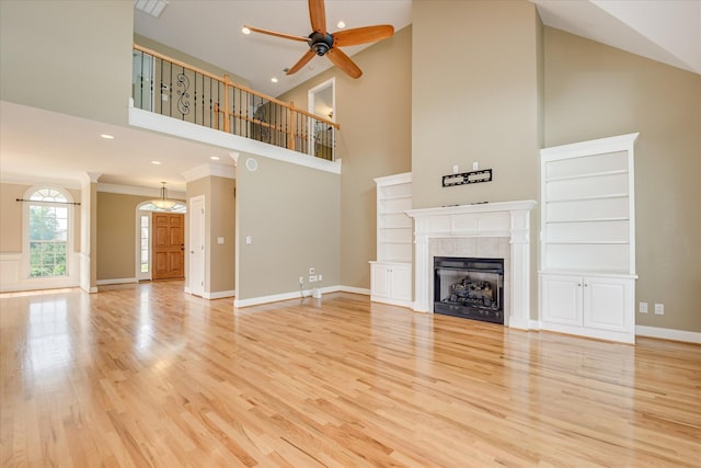 unfurnished living room featuring high vaulted ceiling, ceiling fan, a tiled fireplace, light wood finished floors, and recessed lighting