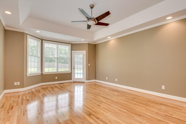 empty room featuring light wood-type flooring, a raised ceiling, crown molding, a ceiling fan, and recessed lighting