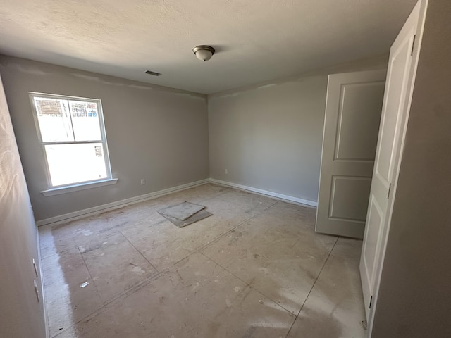 unfurnished room with baseboards, visible vents, and a textured ceiling