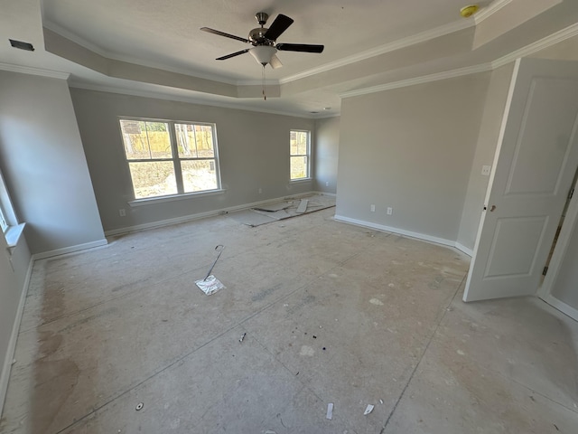 empty room featuring ceiling fan, baseboards, a raised ceiling, and ornamental molding