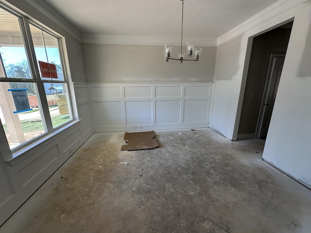 unfurnished dining area with ornamental molding, an inviting chandelier, and a decorative wall