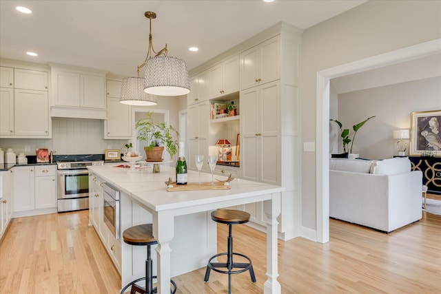 81 Two Mile Dr, Johnston, SC 29832 - kitchen featuring stainless steel appliances, light wood-type flooring, a kitchen island, a kitchen breakfast bar, and white cabinets