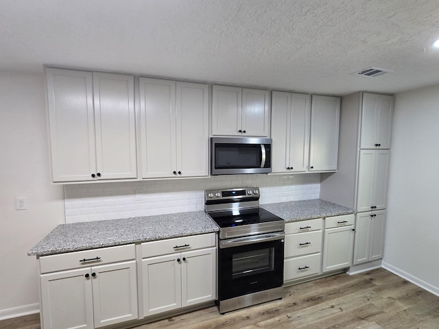 469 Lawrence Dr, Evans, GA 30809 - kitchen with stainless steel appliances, light wood-style flooring, decorative backsplash, light stone counters, and a textured ceiling