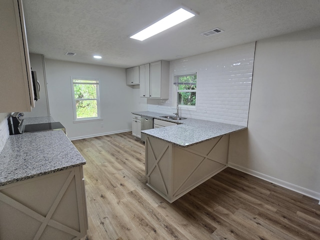 469 Lawrence Dr, Evans, GA 30809 - kitchen with a peninsula, light wood-style flooring, a textured ceiling, light stone countertops, and range with electric cooktop