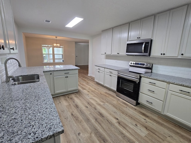 469 Lawrence Dr, Evans, GA 30809 - kitchen with appliances with stainless steel finishes, a chandelier, backsplash, light wood-style floors, and light stone counters