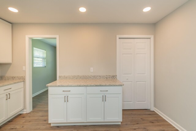 kitchen with light stone countertops, white cabinetry, and light hardwood / wood-style flooring