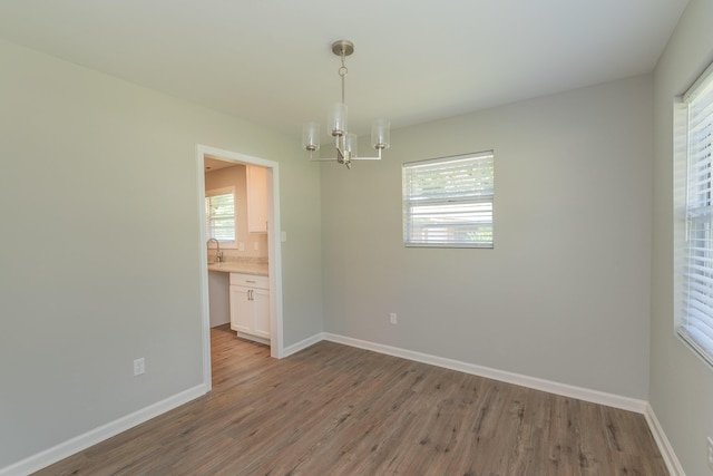 empty room with light hardwood / wood-style floors and an inviting chandelier