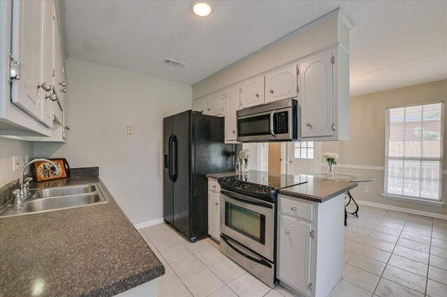 4171 Arlington Rd, Evans, GA 30809 - kitchen featuring appliances with stainless steel finishes, dark countertops, light tile patterned floors, and a peninsula