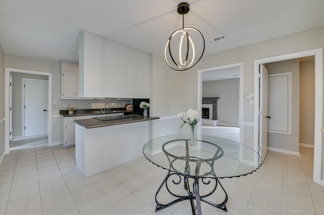 4171 Arlington Rd, Evans, GA 30809 - kitchen featuring dark countertops, a peninsula, white cabinetry, light tile patterned floors, and hanging light fixtures