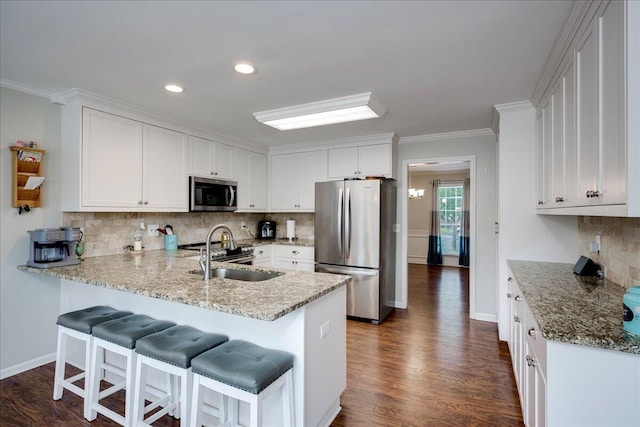 4478 Amanda Ct, Evans, GA 30809 - kitchen featuring stainless steel appliances, a peninsula, decorative backsplash, white cabinetry, and a kitchen breakfast bar