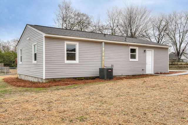 rear view of property with cooling unit and a yard