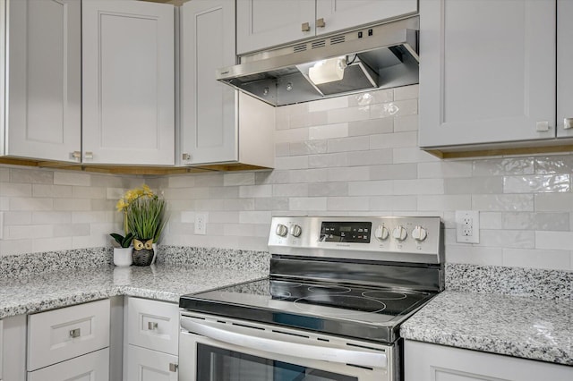 kitchen featuring light stone counters, decorative backsplash, stainless steel range with electric cooktop, and white cabinets