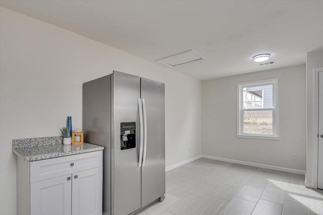 kitchen with white cabinetry, stainless steel refrigerator with ice dispenser, and light stone countertops