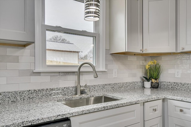 kitchen featuring tasteful backsplash, white cabinetry, sink, and light stone counters