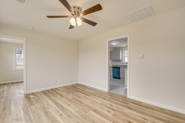 empty room with a wealth of natural light, ceiling fan, and light hardwood / wood-style flooring