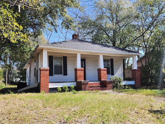 219 S Guignard Dr, Sumter, SC 29150 - view of front of property featuring a chimney, roof with shingles, a porch, and a front lawn