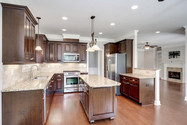 216 Dixon Ct, Evans, GA 30809 - kitchen with stainless steel appliances, ceiling fan, ornamental molding, light stone counters, and a fireplace