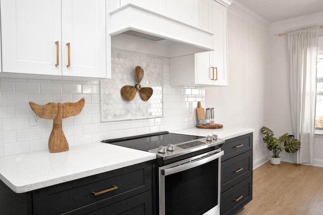 kitchen featuring crown molding, stainless steel range with electric stovetop, custom range hood, and white cabinets