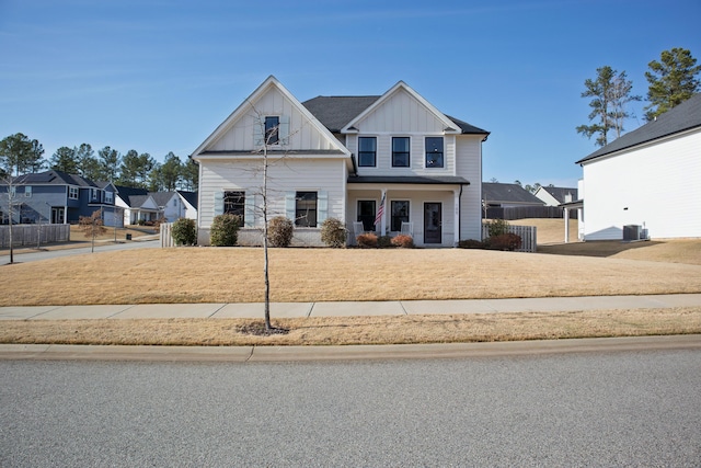 view of front of property featuring central AC unit, board and batten siding, a front lawn, and fence