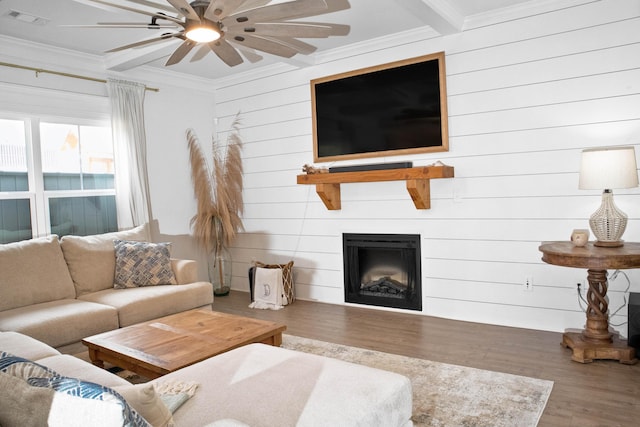 living area with a ceiling fan, wood finished floors, visible vents, a fireplace, and crown molding