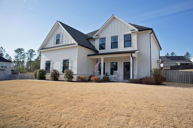 modern inspired farmhouse featuring covered porch, board and batten siding, a front yard, and fence