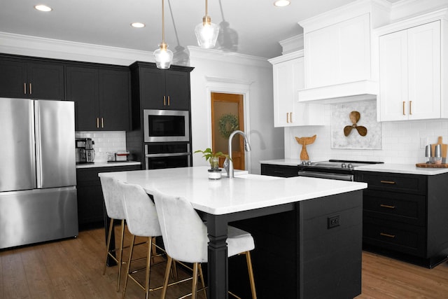 kitchen with a sink, ornamental molding, appliances with stainless steel finishes, and dark cabinets