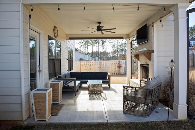 view of patio / terrace featuring an outdoor living space with a fireplace, a ceiling fan, and fence