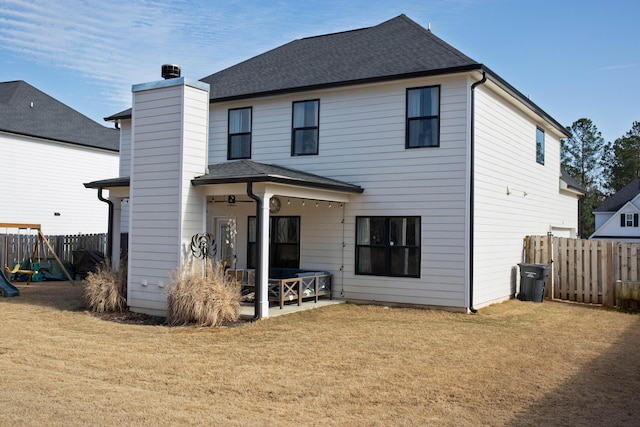 back of property with a patio, a playground, fence, a yard, and a chimney