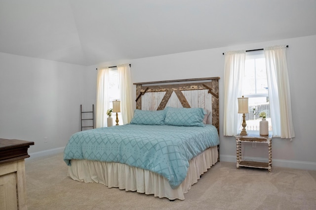 bedroom featuring baseboards, light colored carpet, and lofted ceiling